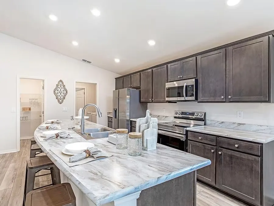 Open kitchen with dark wood cabinets and marble-look countertops