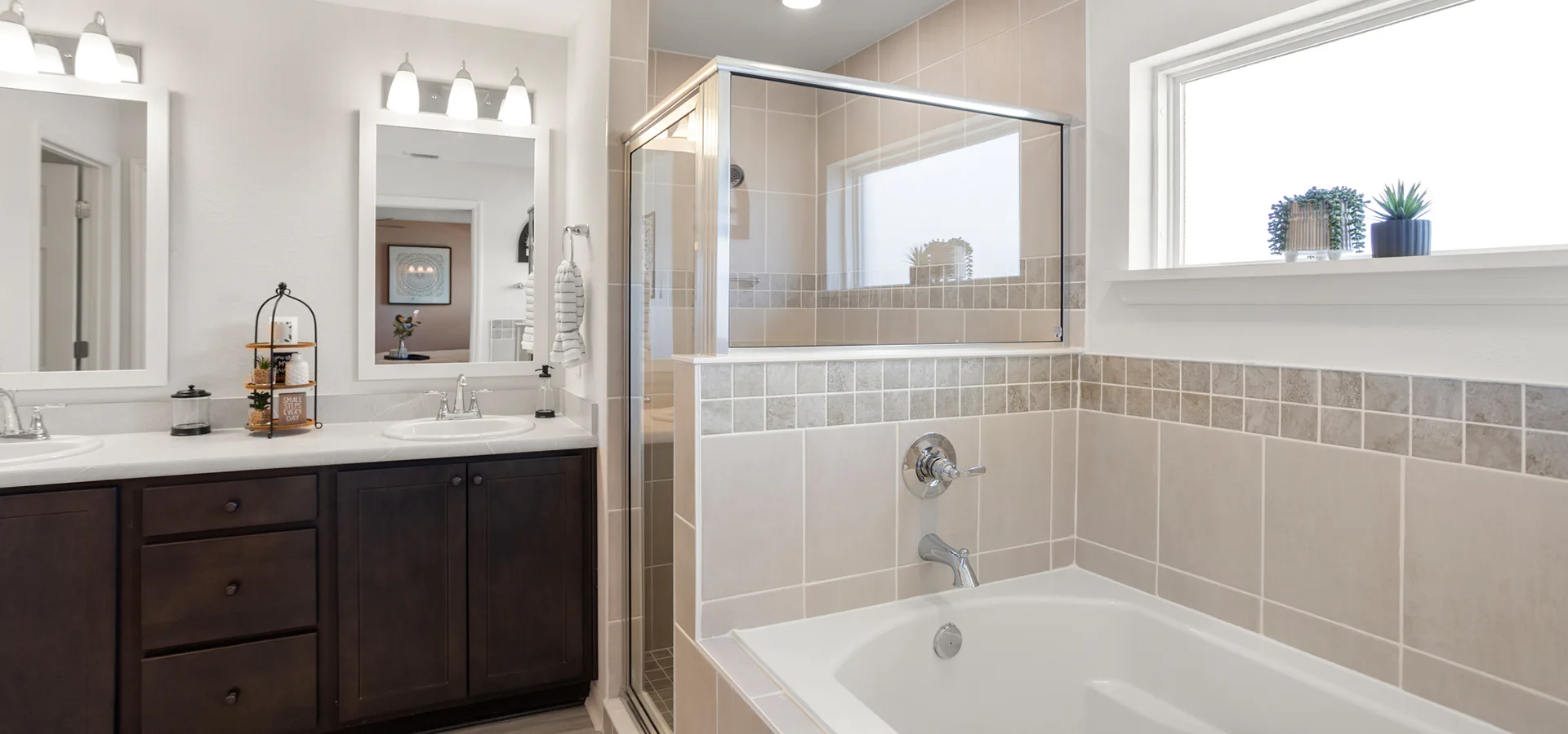 A bathroom with a garden tub, tiled shower, and dual vanities with dark wood cabinets.