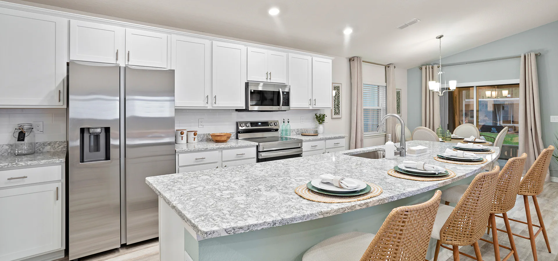 Bright, open kitchen with white cabinets, quartz counters, and a large island
