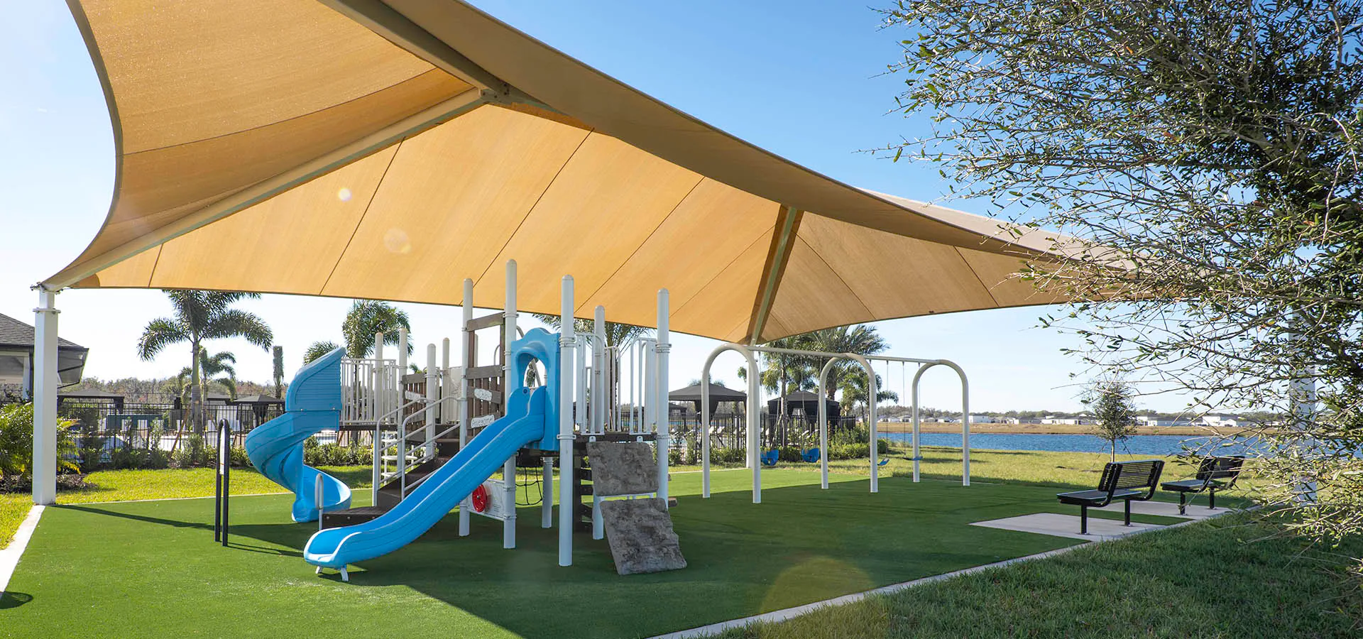 Shaded neighborhood playground with benches at Cypress Ridge Ranch