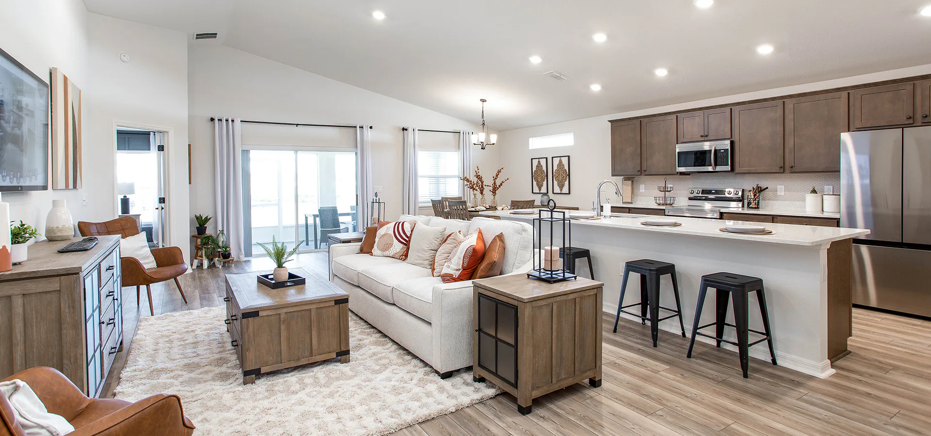 Open-concept living area with rustic wood flooring and furnishings, and rust-colored accents