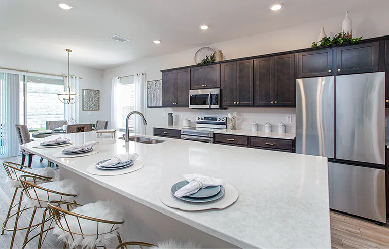 Kitchen with a large island, wood cabinets, quartz counters, and bright brass accents adding a glam decor touch.