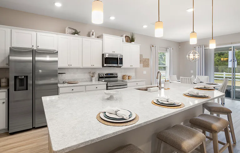 Bright, open kitchen with white cabinets and quartz, a large island, and adjacent dining.